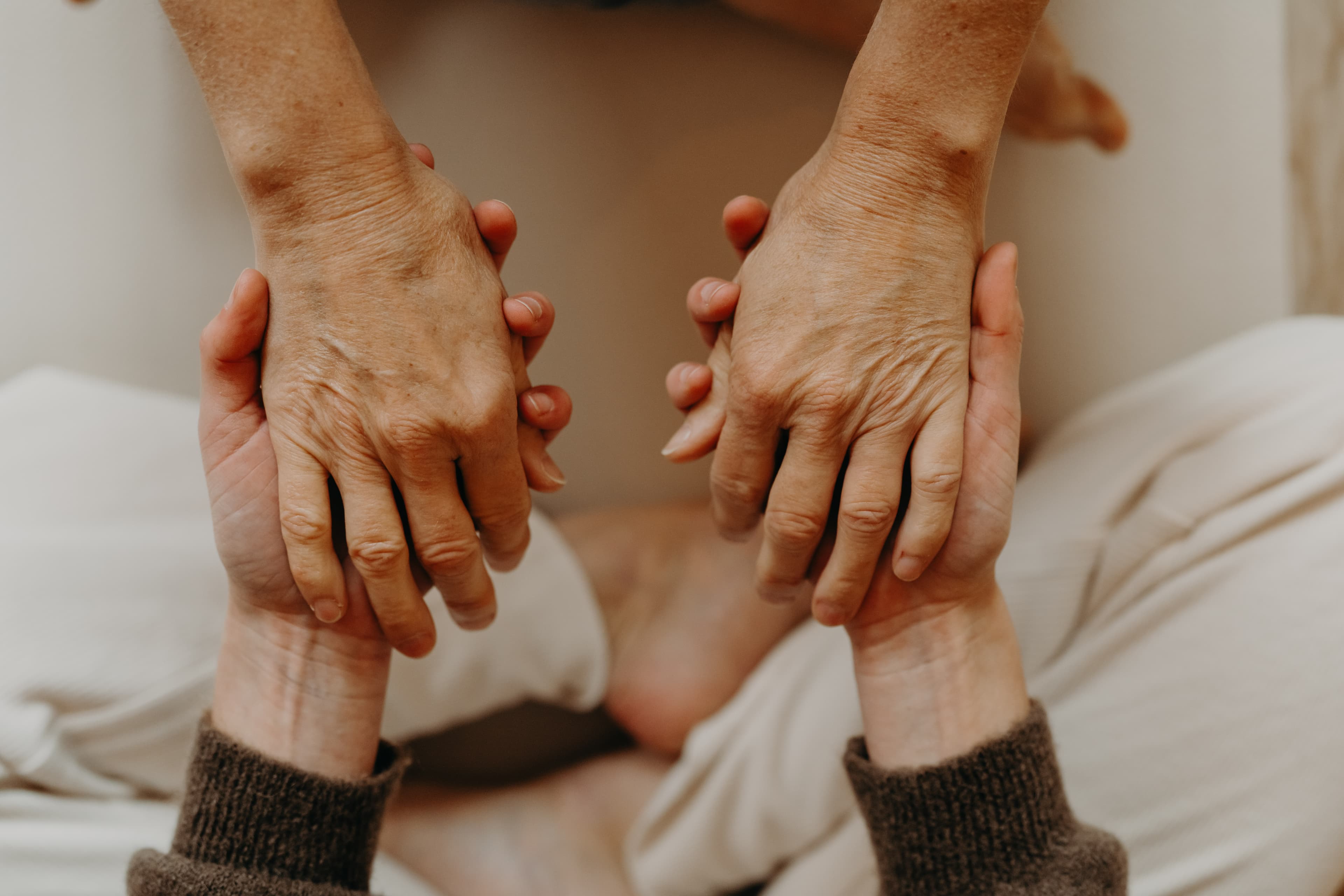 Deux mains accompagnent d'autres mains — symbole du soin et de la relation thérapeutique